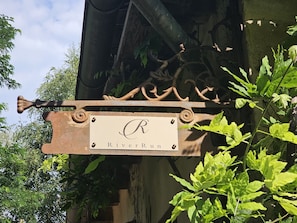 Une enseigne en métal au style rustique, portant l’inscription « RiverRun », est fixée à un bâtiment.