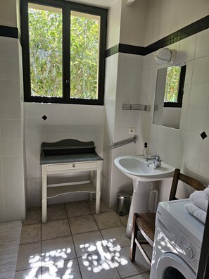 A bathroom with a sink, mirror, window, and a washing machine.