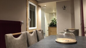 Un espace repas comprenant une table, des chaises, un centre de table en forme de dôme de verre, un meuble en bois et une plante.