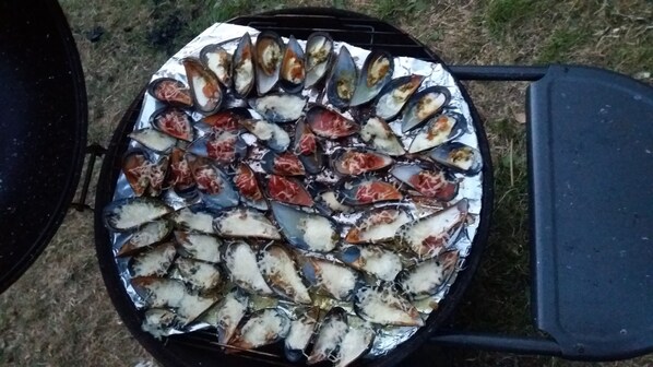 Uma churrasqueira com mexilhões e outros frutos do mar.