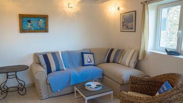 A living room with a sofa, a small table, and a wicker chair.