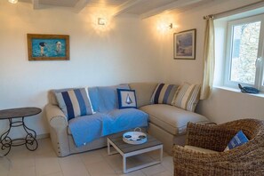 Un salon avec un canapé, une petite table et un fauteuil en osier.
