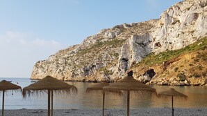 A rocky beach with umbrellas and a cliff.