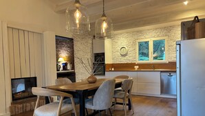 A modern kitchen with a stone wall backsplash, wooden flooring, and a dining area with a wooden table and chairs. - Villa 6 people swimming pool port vecchio (Porto vecchio)