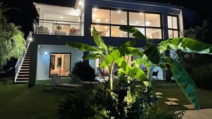 Una casa moderna de dos pisos con balcón, piscina e interior bien iluminado.