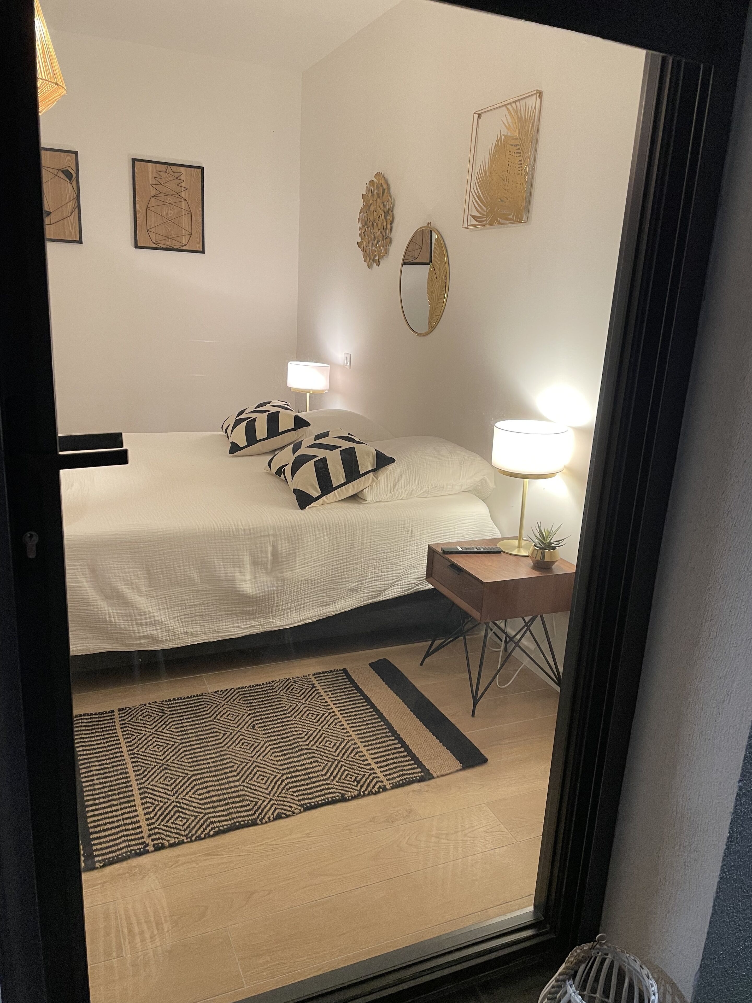 A hotel room with a bed, two bedside tables with lamps, a mirror, and decorative wall art.