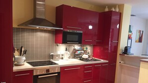 A modern kitchen with red cabinets, a Bosch oven, a microwave, and a stainless steel range hood. - House La Ciotat, near beach and town center (La Ciotat)