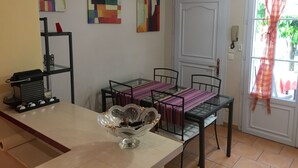 A dining area with a glass table, chairs, and a decorative bowl. There are abstract paintings on the wall and a window with curtains. - House La Ciotat, near beach and town center (La Ciotat)