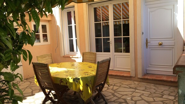 A patio with a round table and four chairs, a white door, and a window with striped curtains. - House La Ciotat, near beach and town center (La Ciotat)