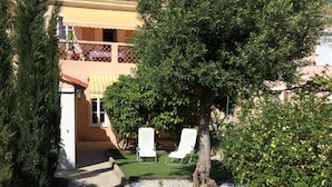 A pathway leading to a building with a yellow facade and a tiled roof. There are two white lounge chairs under a tree. - House La Ciotat, near beach and town center (La Ciotat)