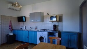 A compact kitchen with blue cabinets, a washing machine, a microwave, and a gas stove. - Small cozy nest for peaceful vacations (Lucciana)