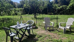 An outdoor seating area with a table and chairs, surrounded by a grassy field and trees. - Small cozy nest for peaceful vacations (Lucciana)