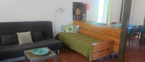 Una sala de estar con un sofá, una mesita y un banco de madera. Se ve un ventanal con vistas al exterior.