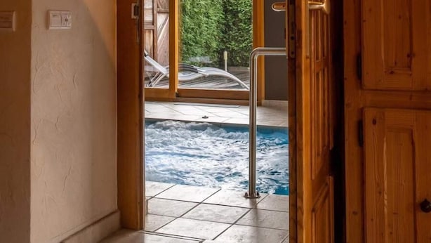 A hallway leading to a glass door with a view of a swimming pool and greenery outside. - LES AMARYLLIS - Le Buet (Taninges)