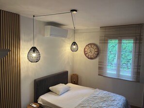 Un dormitorio con cama, un reloj de pared y luces colgantes.