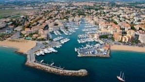 An aerial view of a coastal town with a marina, sandy beaches, and residential buildings.