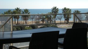 A balcony with a view of the beach and ocean.