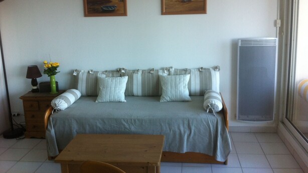 Una habitación con una cama, una mesa, una lámpara y dos cuadros en la pared.