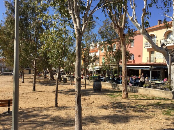 An outdoor seating area with tables and chairs, surrounded by trees and a dirt ground. - 40m2 duplex, sleeps 4 in the heart of the village on the island of Porquerolles (Hyères)