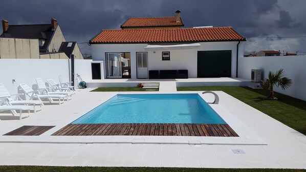 A modern house with a swimming pool, white walls, and a red-tiled roof.