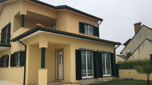A two-story house with a beige exterior, black shutters, and a tiled roof. - House Aveiro heated pool (Gafanha do Carmo)