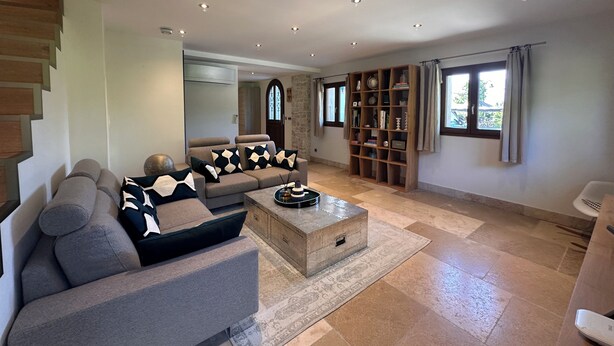 A modern living room with a sofa, a coffee table, a bookshelf, and a staircase.