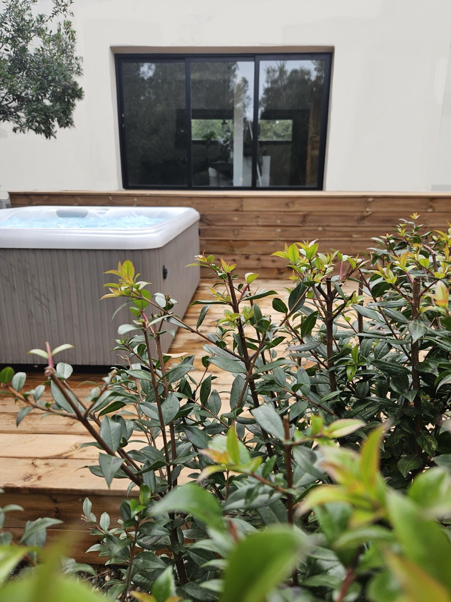 A hot tub on a wooden deck with a window in the background.