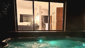 A hot tub with a view of a room through a window.