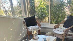 A cozy outdoor seating area with wicker chairs, a white table, and a blue blanket. - Charming old village house, very quiet, wooded garden, sleeps 4. (Paradou)