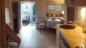A kitchen with a sink, a dining table with chairs, and a window above the table. - Charming old village house, very quiet, wooded garden, sleeps 4. (Paradou)