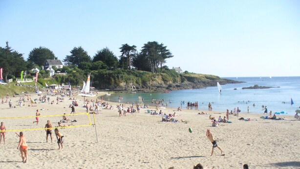 Ein überfüllter Strand mit Menschen, die sich sonnen und schwimmen.