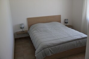 A single bed with a wooden headboard, two bedside tables with lamps, and a tiled floor. - Vacation villa in quiet neighborhood near town center (Pernes-Les-Fontaines)
