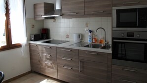 Una cocina moderna con armarios de madera, un lavamanos de acero inoxidable, un microondas y un horno.