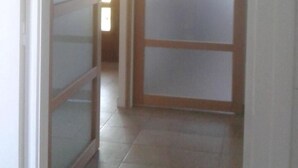 Un pasillo con una puerta de vidrio corredera y vista a otra habitación.