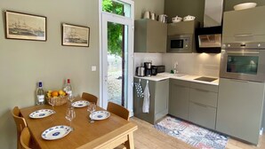 Una cucina moderna con mobili grigi, elettrodomestici in acciaio inossidabile e una zona pranzo con tavolo e sedie in legno.