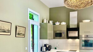 Una cucina moderna con zona pranzo, caratterizzata da un tavolo in legno, sedie e un lampadario in vimini.