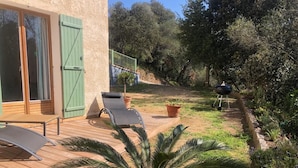 Eine Terrasse mit Holzboden, eine Sitzecke mit Tisch und Stühlen sowie ein großer Kübel mit Pflanze.