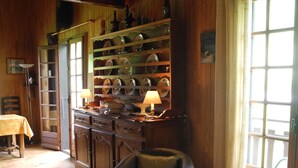 Un cuarto acogedor con paredes de madera, suelo de baldosas, una silla, un sofá, una mesa y una estantería con objetos decorativos.