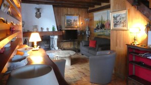 Una sala de estar acogedora con chimenea, vigas de madera, un sofá y una mesa de centro.