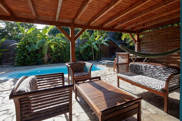 A wooden deck with a pool, lounge chairs, and a hammock. - kaz a coco, blue villa with private pool (Deshaies)