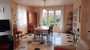 A living room with a TV, a dining table, and a sofa. - Spacious and pleasant house (Castelnau-De-Guers)