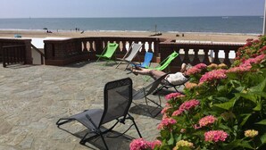 Une terrasse avec un sol en pierre, un mur en briques et une vue sur la plage.