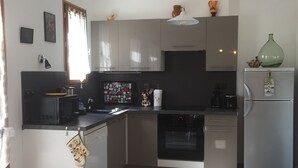A modern kitchen with a dining area, featuring stainless steel appliances, a microwave, and a refrigerator. - Holiday house in Provence (Lauris)