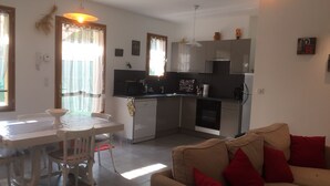 A modern kitchen with a dining area, a sofa, and a table with chairs. - Holiday house in Provence (Lauris)