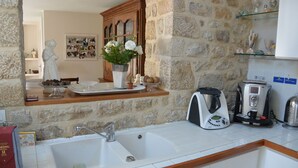 A kitchen with a stone wall, a sink, a coffee maker, and a cabinet with glass doors.