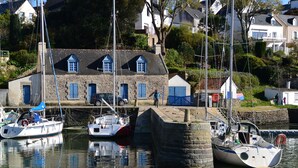 A harbor with boats docked near a stone building with blue shutters.