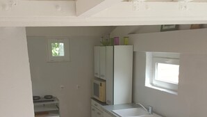 Une cuisine de taille réduite avec des meubles blancs, un évier et une fenêtre.