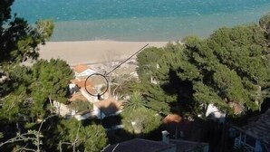 Une vue sur la plage, avec un ciel dégagé, entourée d’une végétation luxuriante et de quelques bâtiments.