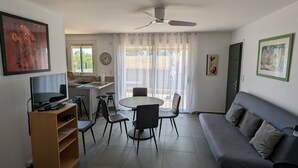 A compact living space with a dining area, a sofa, a TV, and a kitchen area. - Appt Leucate- La Franqui.  3 rooms, beach at 50 m, Terrace, free Wifi, (Leucate)