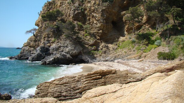Une côte rocheuse offrant une vue dégagée sur la mer et une falaise à la végétation clairsemée.